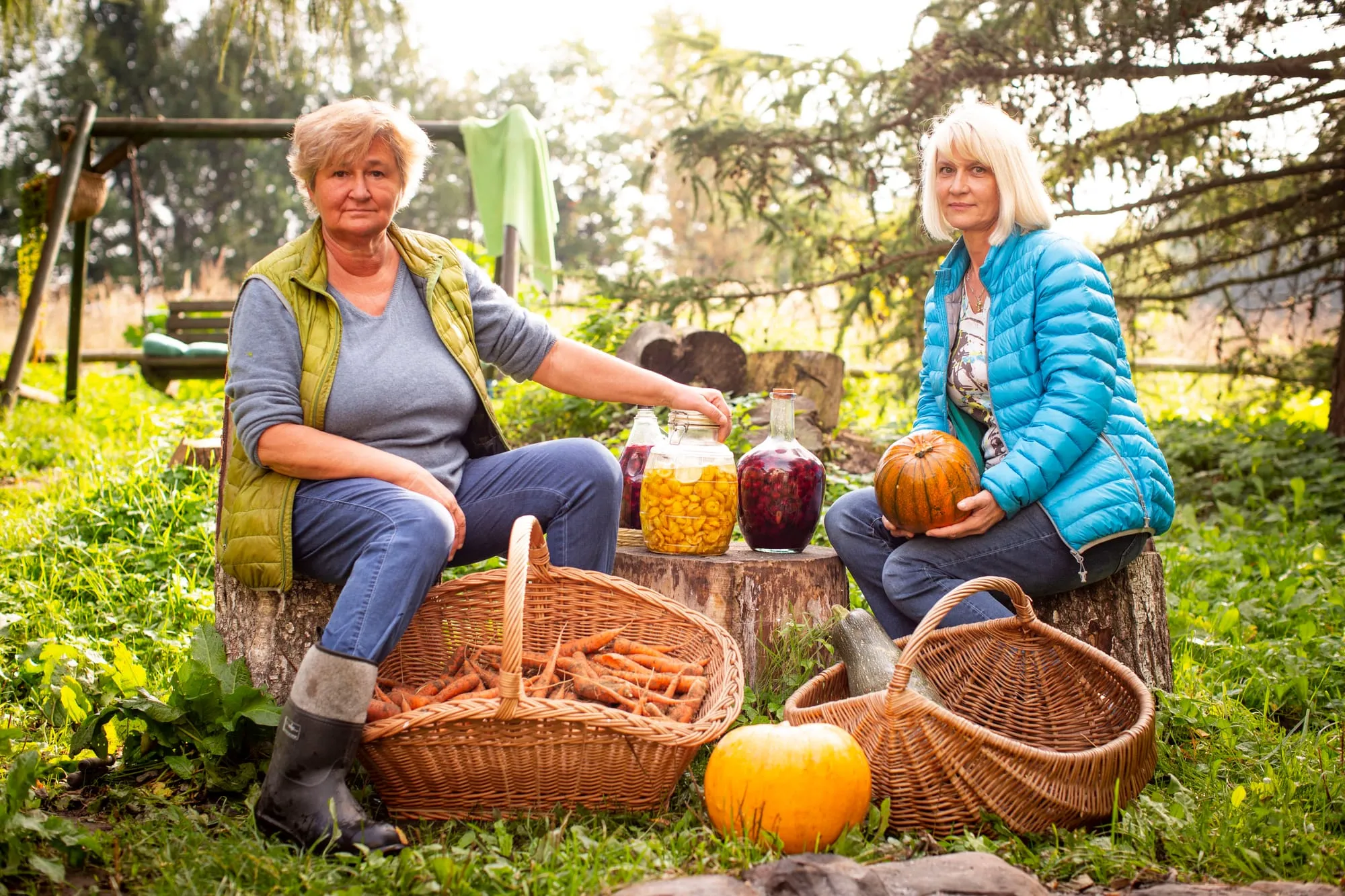 Dwie kobiety z koszami dyń i słojami w ogrodzie